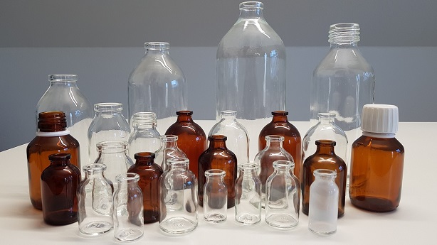 Many glass bottles in clear and brown next to each other on a table